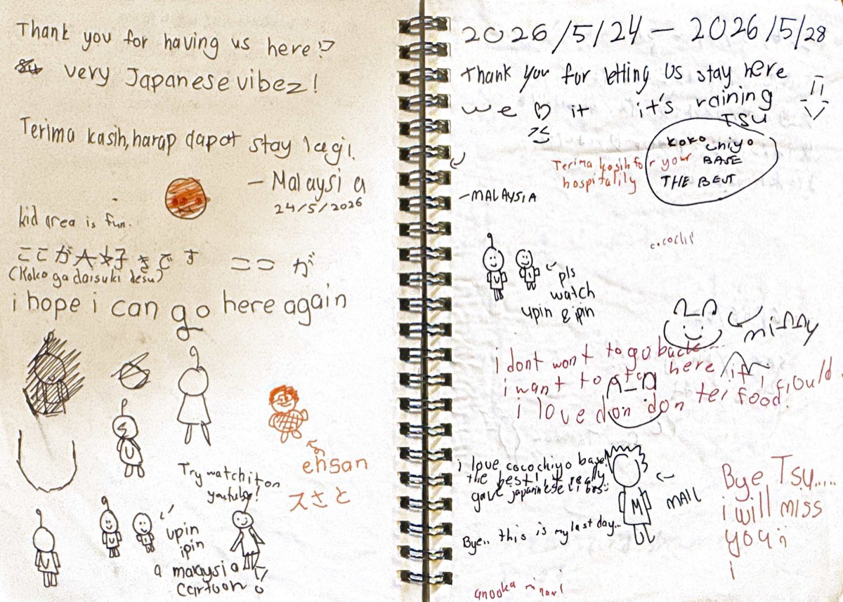 An open guest notebook decorated with several languages and illustrations.